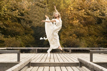 Ballerina tanzt im weißen Kleid, springt auf Holzsteg - FCF01826