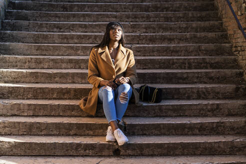 Weibliche Touristin sitzt auf einer Treppe im Freien - GIOF07282