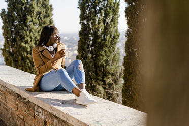 Weiblicher Tourist mit einem Kaffee zum Mitnehmen mit Blick auf die Aussicht im Freien - GIOF07286