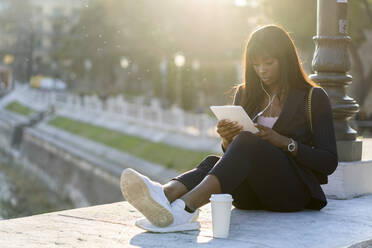 Businesswoman sitting outdoors using a digital tablet - GIOF07296