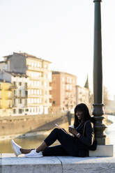 Smiling businesswoman sitting outdoors using a digital tablet - GIOF07299