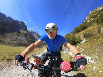 Ein älterer Mann fährt mit seinem elektrischen Mountainbike durch die Alpen - LAF02383