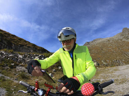 Älterer Mann mit seinem elektrischen Mountainbike in den Alpen - LAF02384