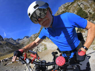 Älterer Mann mit seinem elektrischen Mountainbike in den Alpen - LAF02385