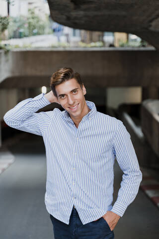 Portrait of a smiling young stylish man outdoors stock photo