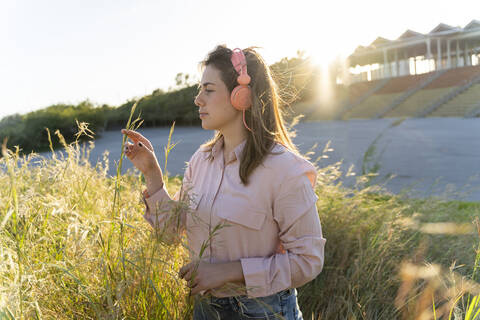 Junge Frau hört Musik mit Kopfhörern im Freien, lizenzfreies Stockfoto