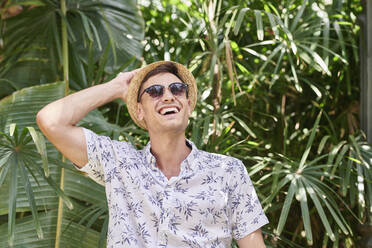 Lächelnder Mann mit Hut und Sonnenbrille in einem Park - JNDF00141