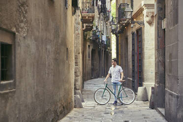 Man standing with his bicycle in a narrow alley - JNDF00142