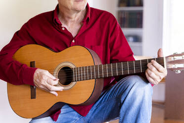 Älterer Mann spielt Gitarre zu Hause - AFVF04133