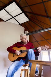 Älterer Mann spielt Gitarre zu Hause - AFVF04134