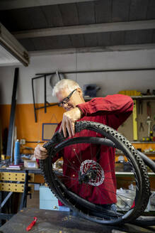 Älterer Mann repariert Fahrradreifen in der Garage - AFVF04138