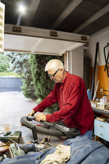 Älterer Mann repariert Fahrradreifen in der Garage - AFVF04139