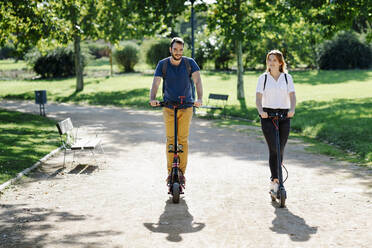 Pärchen auf Elektrorollern in einem Stadtpark - JSMF01317