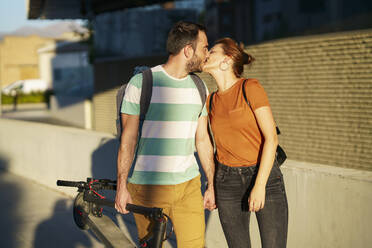 Kissing couple with folded electric scooter - JSMF01355