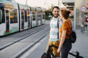 Ehepaar mit gefaltetem Elektroroller wartet an der Straßenbahnhaltestelle - JSMF01363