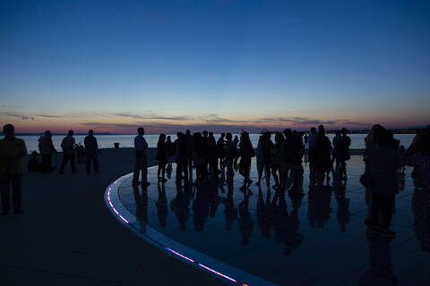 Kroatien, Zadar, Silhouetten von Menschen besuchen Meer Orgel in der Abenddämmerung, lizenzfreies Stockfoto