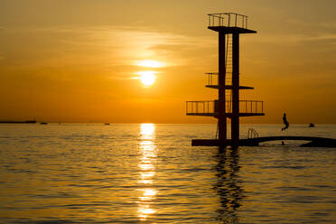 Kroatien, Zatar, Silhouette einer Tauchplattform an der Küste bei Sonnenuntergang - NGF00538