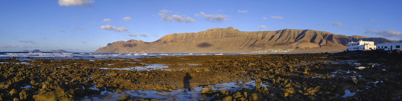 Spanien, Kanarische Inseln, Caleta de Famara, Panorama der felsigen Meeresküste mit Risco de Famara im Hintergrund - SIEF09188