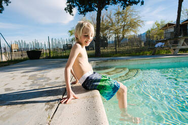 Junge sitzt am Swimmingpool, Olancha, Kalifornien, USA - ISF22216