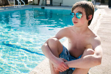 Boy sitting by swimming pool - ISF22217