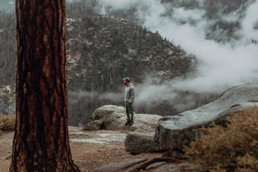 Wanderer genießt den Blick auf das nebelverhangene Tal, Yosemite National Park, Kalifornien, Vereinigte Staaten - ISF22314