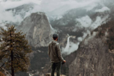 Wanderer genießt den Blick auf das nebelverhangene Tal, Yosemite National Park, Kalifornien, Vereinigte Staaten - ISF22315