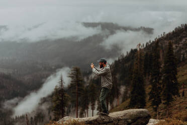 Wanderer, der den Blick auf das nebelverhangene Tal fotografiert, Yosemite-Nationalpark, Kalifornien, Vereinigte Staaten - ISF22316