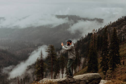 Hiker taking photograph of view of fog covering valley, Yosemite National Park, California, United States - ISF22316