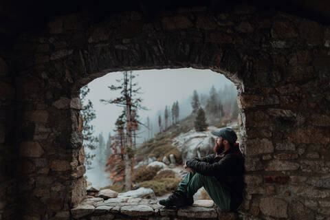 Wanderer, der auf einem Felsvorsprung die Aussicht auf ein nebliges Tal genießt, Yosemite National Park, Kalifornien, Vereinigte Staaten, lizenzfreies Stockfoto