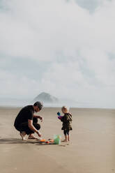 Vater und Kleinkind spielen mit Sand am Strand, Morro Bay, Kalifornien, Vereinigte Staaten - ISF22334