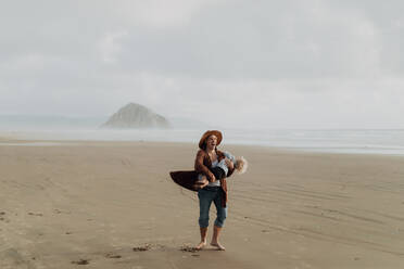 Mother and toddler playing with sand on beach, Morro Bay, California, United States - ISF22335