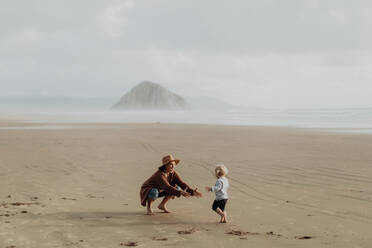 Mutter und Kleinkind spielen mit Sand am Strand, Morro Bay, Kalifornien, Vereinigte Staaten - ISF22336