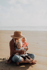 Mutter und Kinder sitzen am Strand - ISF22345