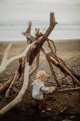 Toddler playing beside wickiup on beach - ISF22354