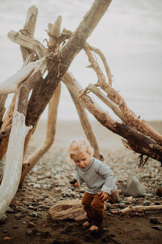 Kleinkind spielt neben Wickiup am Strand, lizenzfreies Stockfoto