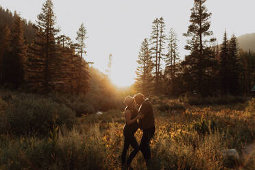 Pregnant mid adult couple face to face in rural valley at sunset, Mineral King, California, USA - ISF22376