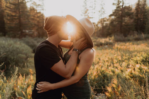 Pregnant mid adult couple about to kiss in rural valley at sunset, Mineral King, California, USA - ISF22378