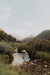 Junge Frau mit Stetson überquert Trittsteine in ländlichem Fluss, Mineral King, Kalifornien, USA - ISF22394