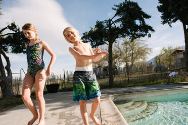 Bruder und Schwester spielen am Swimmingpool, Olancha, Kalifornien, USA - ISF22428