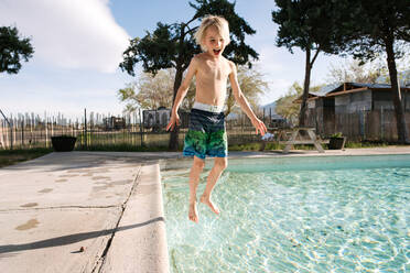 Boy jumping into swimming pool, Olancha, California, US - ISF22429