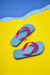 Pair of colourful flip-flops on sandy beach by sea - ISF22448