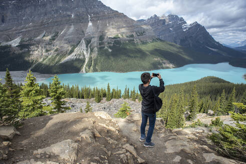 Teenage boy taking a cell phone photo of Peyto Lake in the Rockies. - CAVF65669