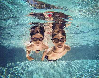 Unterwasserbild von zwei Jungen, die nebeneinander in einem Pool schwimmen. - CAVF65689