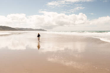 Tween girl running on beach with reflection - CAVF65720