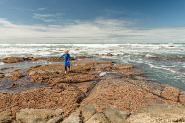 Kleiner Junge erkundet die neuseeländische Felsenküste - CAVF65725