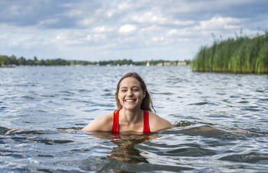 Porträt einer lächelnden Frau beim Baden in einem See - BFRF02120