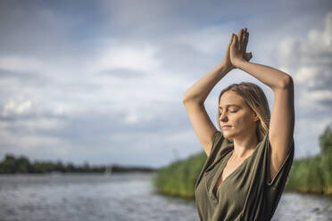 Woman meditating at a lake - BFRF02128