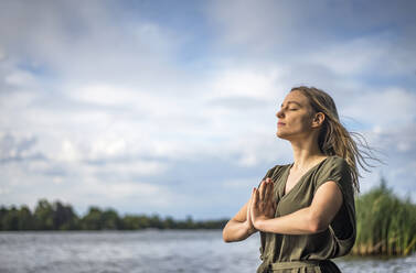 Frau meditiert an einem See - BFRF02129