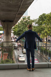 Rear view of young businessman on pedestrian bridge - MAUF02993