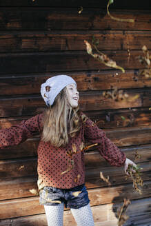 Lächelndes Mädchen vor einer Holzwand im Freien stehend - HMEF00654